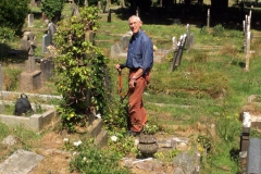 Volunteer Bob clearing ivy off headstones ready to read and record.
